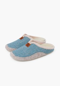 Kapcie w niebieski wzór w jodełkę z jasnobeżowym wykończeniem i brązową skórzaną metką. Miękki materiał tekstylny z puszystą podszewką wewnętrzną.