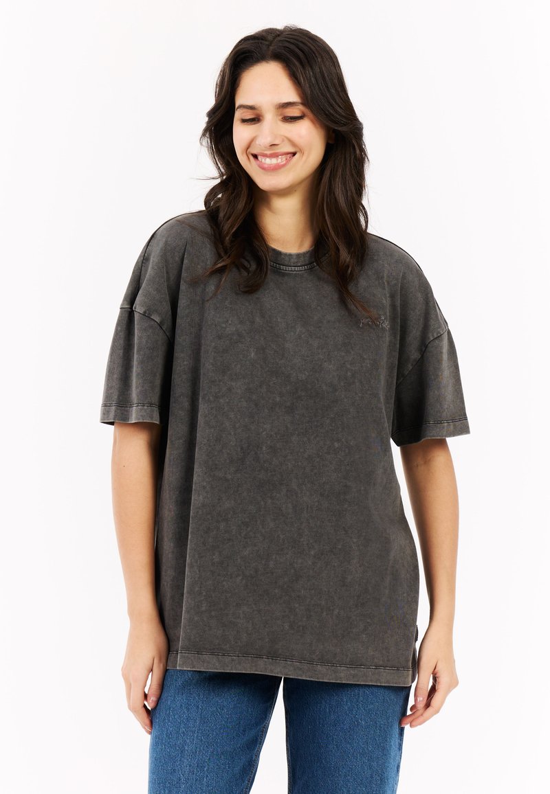 Overmaat grijze katoenen t-shirt met een gewassen textuur, korte mouwen, ronde halslijn en subtiele stikdetails, gecombineerd met blauwe jeans.