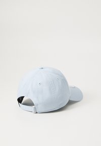 Boné de basebol azul claro feito de tecido, com uma aba curva, faixa ajustável na parte de trás e orifícios de ventilação nos lados.
