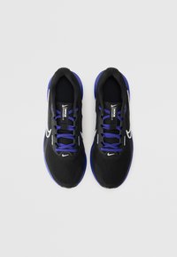 Scarpe da ginnastica nere con tomaia in rete, accenti viola e un logo Nike bianco su ciascun lato. Presentano una suola piatta e lacci a contrasto.
