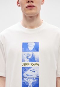 Λευκό μπλουζάκι με τέσσερις μπλε και λευκές πάνελ χαρακτήρων από το "Jujutsu Kaisen", με τον τίτλο σε στυλιζαρισμένο χρυσό κείμενο από κάτω.