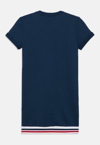 Μπλε ναυτικό t-shirt με κοντά μανίκια και λαιμόκοψη στρογγυλή. Το κάτω μέρος έχει ριγέ μοτίβο με κόκκινες, λευκές και ναυτικές λεπτομέρειες.