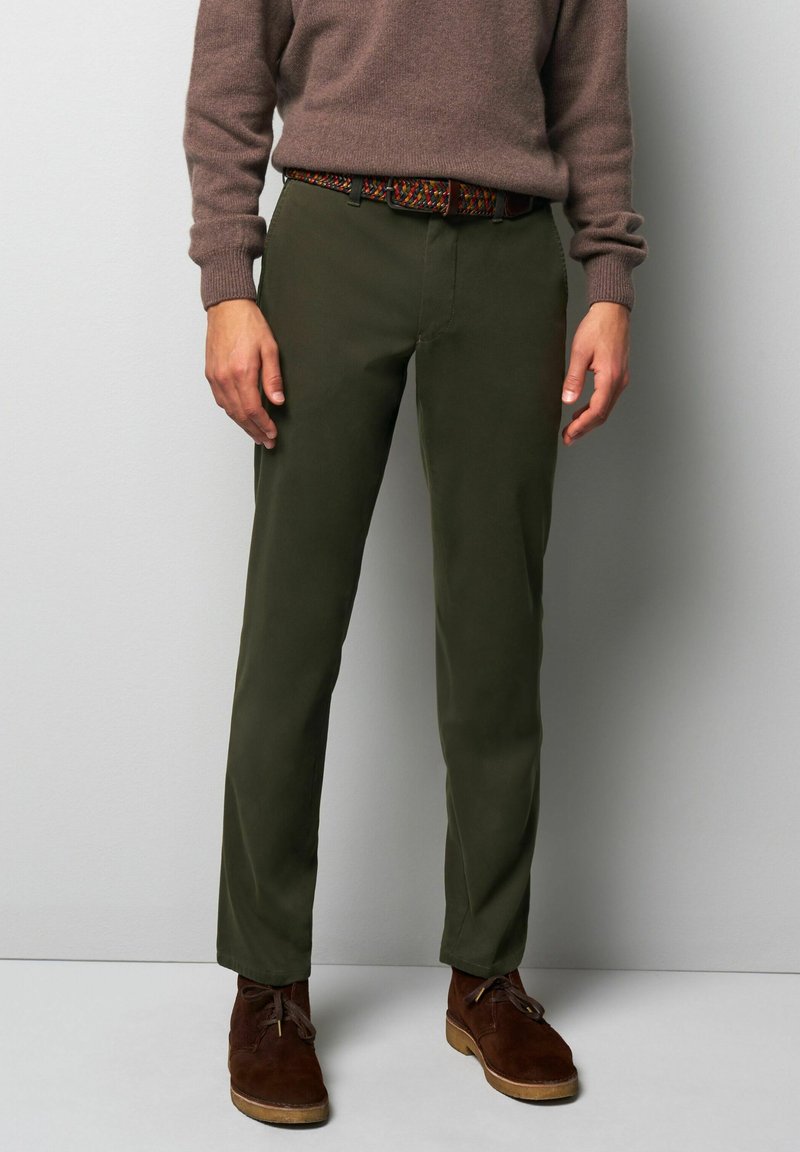Olijfgroene chino's met een rechte pasvorm, gemaakt van katoen. Gecombineerd met een bruine gebreide trui en een ceintuur met een meerkleurig patroon, met daaronder bruine suède schoenen.