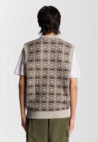 Gilet lavorato a maglia con un motivo geometrico nei toni del beige, marrone e blu, caratterizzato da un collo tondo e design senza maniche, realizzato in tessuto testurizzato.