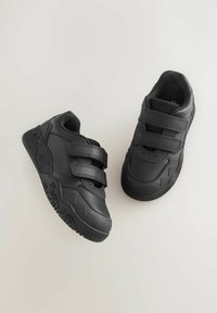 Schwarze Sportschuhe mit zwei Klettverschlüssen, einer strukturierten Gummisohle und einem glatten Obermaterial mit verstärkten Akzenten und seitlichen Details.