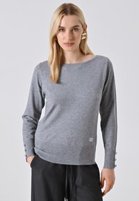Maglione grigio a maniche lunghe con scollo a barca, tessuto testurizzato, orlo a costine e dettagli con bottoni sulle maniche. Logo discreto vicino al fondo.