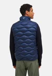 Navy blue puffer vest with a quilted design featuring rounded sections. High collar and smooth, shiny exterior. Suitable for layering.