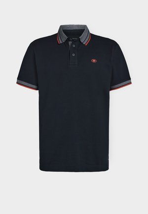 Camiseta polo azul marino con cuello gris en contraste, detalles rojos en las mangas, tapeta de tres botones y pequeño logo en el pecho. Material de algodón.