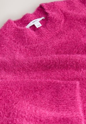 Pull rose pelucheux avec une texture douce, col rond et une poche avant. L'étiquette indique "NEXT". Le design présente une couleur unie sans motifs.