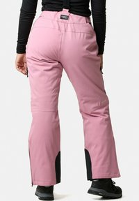 Pink waterproof ski pants with adjustable straps, featuring zippered side pockets and black mesh accents at the ankles.