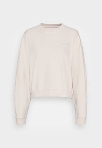 Jasno-beżowy, skrócony sweatshirt z opuszczonymi ramionami, prążkowanymi mankietami i miękką fakturą. Posiada subtelne logo na piersi.