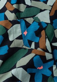Fabrica de catifea cu un model abstract multicolor, cu flori albastre, frunze verzi și forme maronii pe un fundal negru.