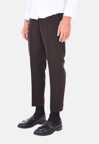 Pantaloni marroni su misura con una vestibilità affusolata, caratterizzati da una texture liscia, orlo con risvolto e dettagli di piega laterale, abbinati a mocassini neri.