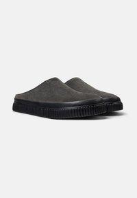 Zapatos slip-on de ante gris con suela de goma negra; textura suave con puntera redondeada y detalles acanalados a lo largo del borde de la suela.