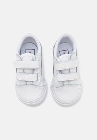 Baskets blanches en cuir avec deux bandes Velcro, bout rond, panneaux latéraux texturés et soutien de cheville rembourré. Semelle en caoutchouc blanc.