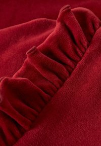 Roter Samtstoff mit gerafften Akzenten, der eine weiche Textur und eine reiche Farbe zeigt. Der Stoff hat ein glattes, plüschiges Aussehen mit subtiler Glanz.