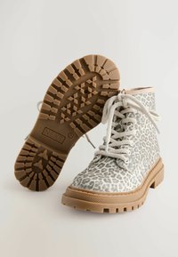Botas de print de leopardo con parte superior de tela gris texturizada, suela de goma beige y cordones blancos. Presenta una suela con relieve para mayor tracción.