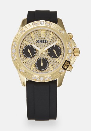 Gold-tone chronograph watch with black silicone strap, sparkling crystal accents, black dial with subdials, and large numeral markers.