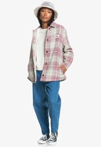 Rutigt jacka i pastelrosa och grön, knapplist fram, sidofickor, kombinerat med blå jeans och svarta sneakers. Vit bucket hat.
