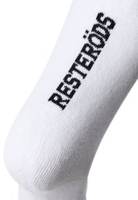 Hvide bomuldsstrømper med sort strikket tekst, der siger "RESTERÖDS," med en glat tekstur og semi-gennemsigtig finish.