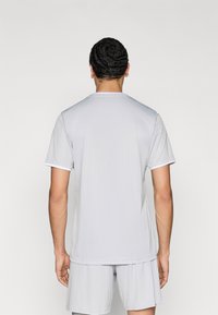 Γκρι αθλητικό μπλουζάκι με κοντά μανίκια, με στρογγυλή λαιμόκοψη και λευκή λεπτομέρεια στο τελείωμα των μανικιών, συνδυασμένο με αντίστοιχα σορτς.