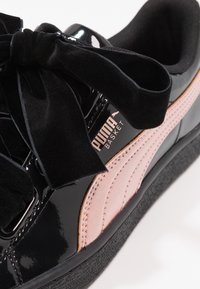 Černé lakované tenisky Puma Basket s velkými černými sametovými šňůrkami ve tvaru mašle a jemným růžovým semišovým páskem.