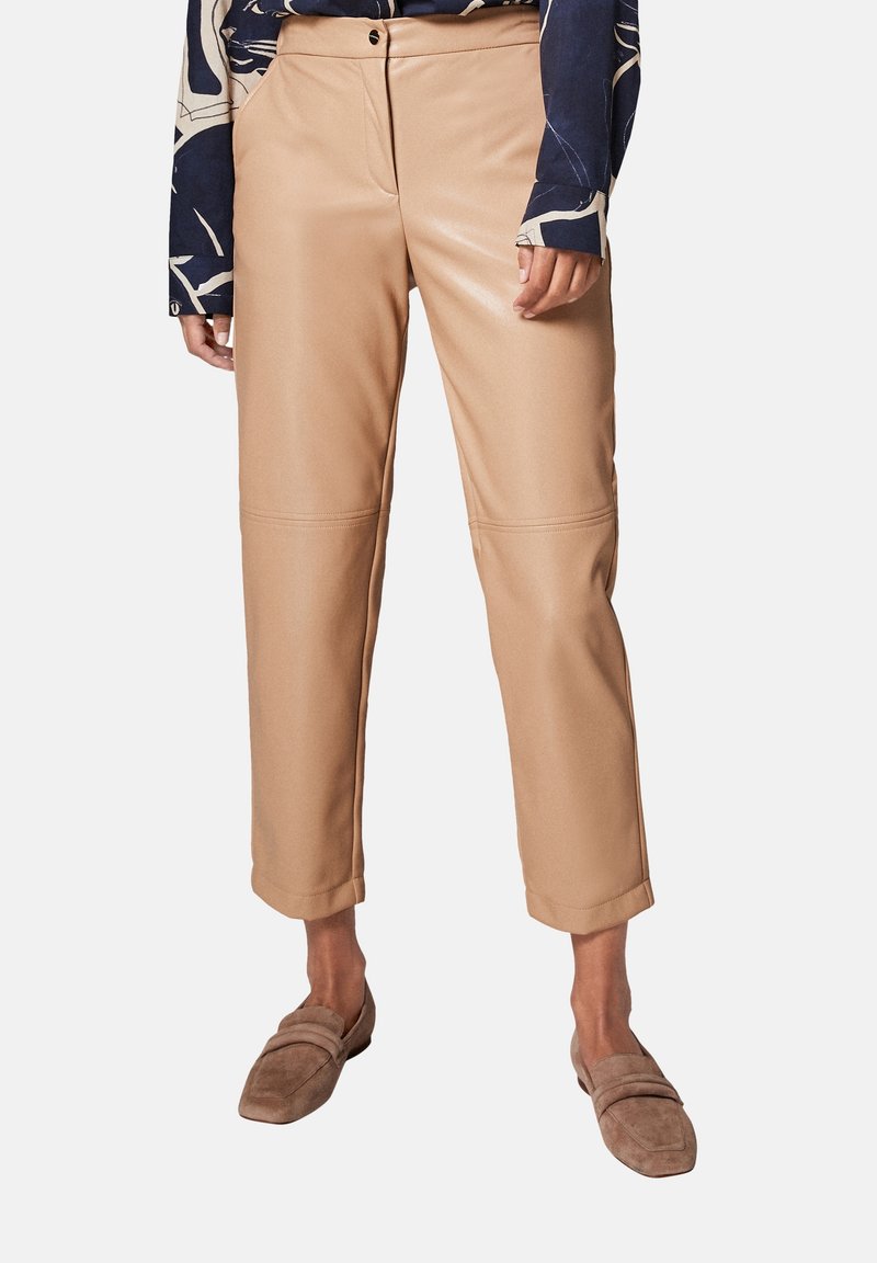 Beige neplederen cropped broek met een gladde textuur, voorzien van stiksels aan de voorkant, gedragen met bruin instap schoenen en een patronen top.