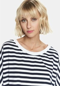 Top w paski w kolorze granatowym i białym, z szerokim dekoltem i krótkimi rękawami, charakteryzujący się miękką, gładką teksturą i luźnym krojem.