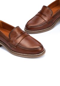 Brown leather loafers with a smooth finish, featuring a penny slot detail and contrast stitching, set on a textured rubber sole.