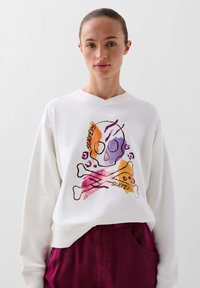 Hanorac alb cu un design grafic care prezintă un schelet, oase încrucișate și accente colorate în purpuriu, portocaliu și roz. Textură moale.