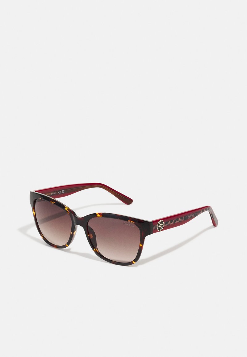 Ochelari de soare cu rame de țestoasă, formă rectangulară, lentile maro cu un gradient și brațe roșii care prezintă un detaliu cu logo aproape de tâmplă.