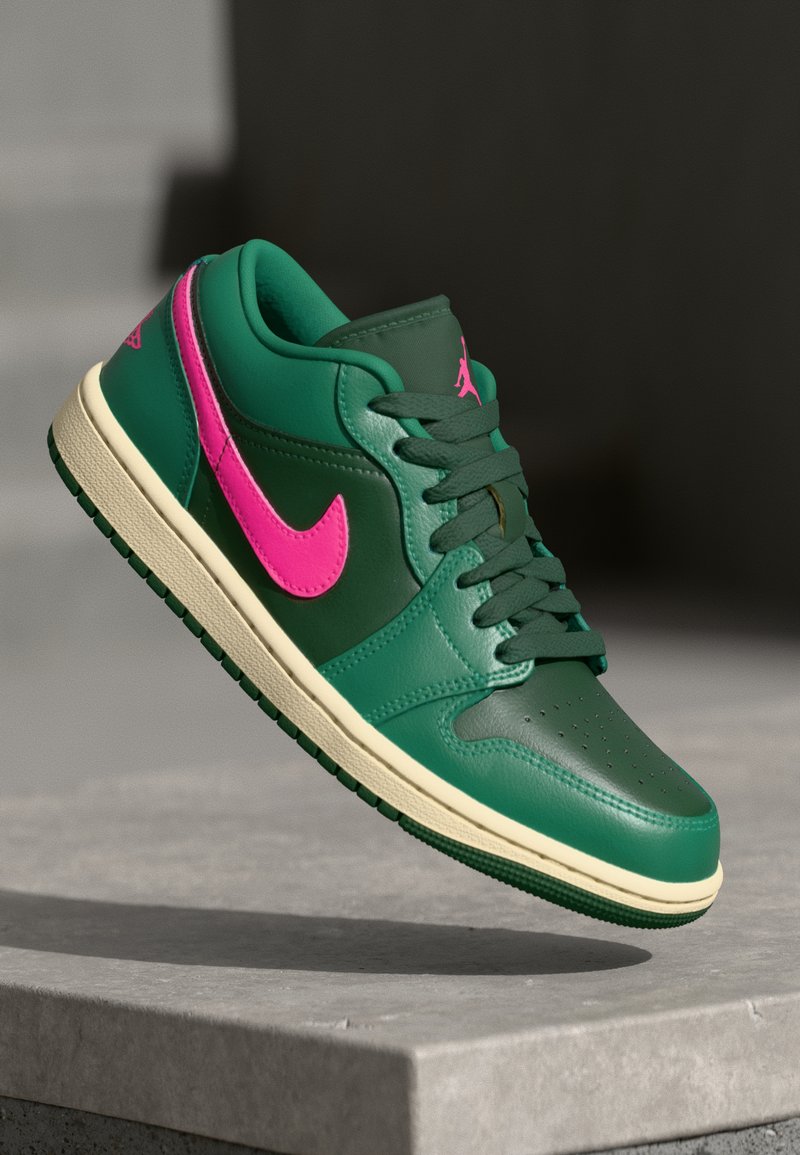 Zaļas ādas kedas ar rozā Nike Swoosh, teksturētu virsu un krēmbaltu zoli. Iespējas ietver auklu aizdari un perforētu pirkstu daļu.