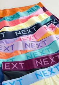 Színes férfi alsónadrágok sorokba rakva, élénk elasztikus derékpántokkal, a "NEXT" márkázással ellentétes árnyalatokban.