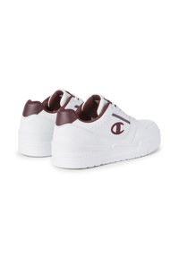 Weiße Sneakers mit kastanienbraunen Akzenten, Obermaterial aus Leder, durchbrochene Details, gepolsterter Schuhkragen und Gummisohle mit strukturiertem Griff.