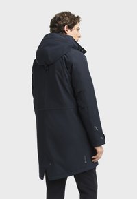 Mornarska vodootporna jakna s kapuljačom, podesivim manžetama i ravnim krojem. Izrađena od izdržljivog materijala s mat završnom obradom.