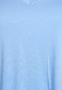 Camiseta de cuello en V azul claro, hecha de suave y liso tejido de algodón. Presenta un diseño sencillo sin patrones ni adornos.