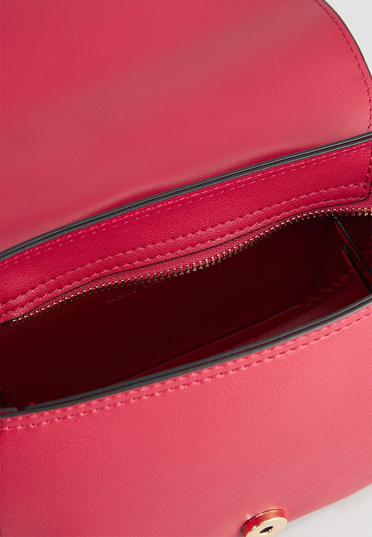 Sac en cuir rouge à la texture lisse, avec un compartiment zippé, des accessoires en ton doré et des coutures noires contrastantes le long des bords.