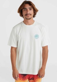 Camiseta de algodón blanca con un logo circular azul que presenta diseños de sol y ola en el lado izquierdo del pecho, con mangas cortas y un corte relajado.