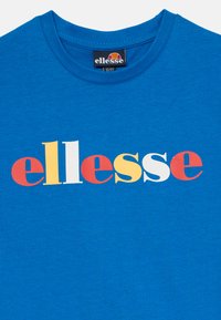 T-shirt in cotone blu con collo rotondo. Il design frontale presenta il logo "ellesse" in lettere blocco multicolori: rosso, giallo, bianco e blu.