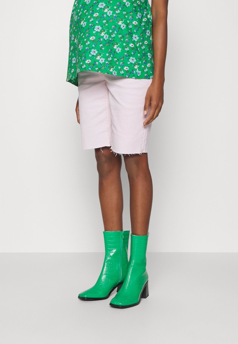 Top floral verde combinado com calções rosa claro e botas de tornozelo verdes com embossido de crocodilo, bico quadrado e salto bloco.