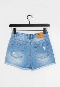 Pantalones cortos de mezclilla en azul claro con dobladillo deshilachado, cuentan con dos bolsillos traseros y una etiqueta de marca de cuero en la cinturilla.