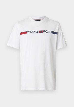 Λευκό βαμβακερό μπλουζάκι με οριζόντιο λογότυπο 'TOMMY HILFIGER' σε ναυτικό μπλε και κόκκινο στο στήθος· κλασικός στρογγυλός λαιμός και κοντά μανίκια.