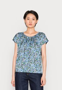 Top floral de manga curta em azul claro com detalhes em verde e preto. Apresenta um decote redondo e leve pregueado na gola.