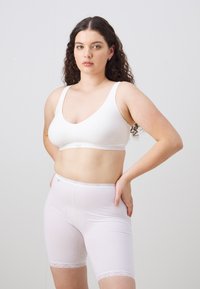 Hvit croppet sports-bh og hvite shorts med midt-lår lengde og blondekant. Begge laget av glatt, elastisk stoff; uformell, tett passform.