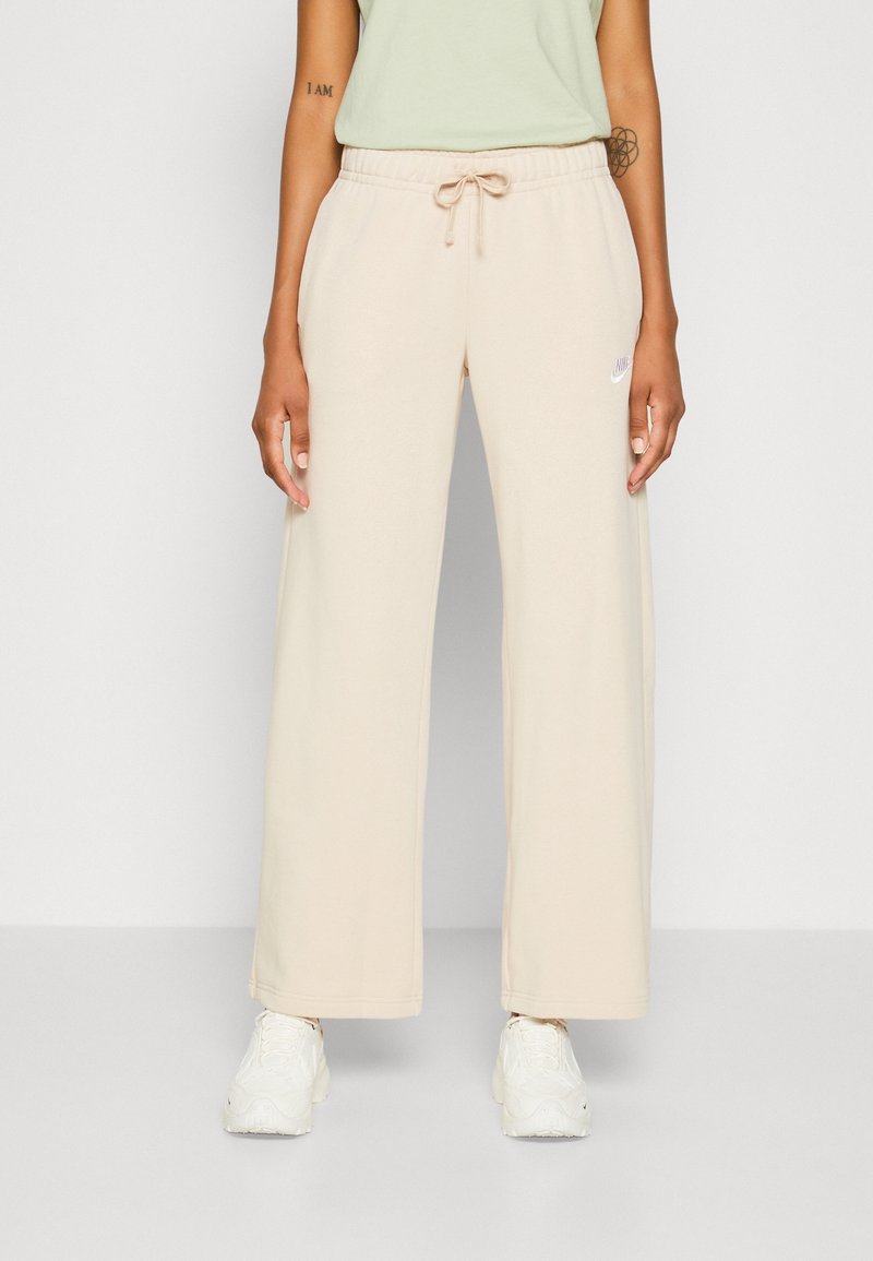 Beige wide-leg sweatpants with an elastic waistband and drawstring, featuring a small white logo on the left side. Soft fabric texture.