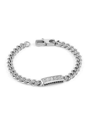 Bracelet en chaîne argentée avec un fini poli, présentant une plaque rectangulaire centrale gravée "GUESS" et une fermeture à crochet.