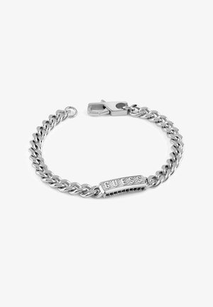 Bracelet en chaîne argentée avec un fini poli, présentant une plaque rectangulaire centrale gravée "GUESS" et une fermeture à crochet.