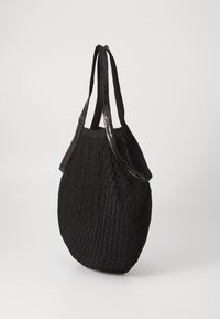 Borsa tote nera intrecciata con un design a rete, dotata di due manici in tessuto e di un accento lucido lungo il bordo superiore. Texture morbida, forma flessibile.