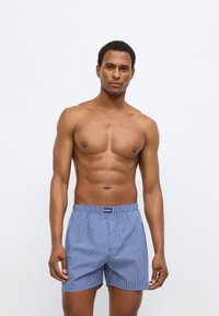 Ανδρικά μπλε καρό μποξεράκια με ελαστική μέση, με διακριτικό μοτίβο πλέγματος, κατασκευασμένα από ελαφρύ ύφασμα.