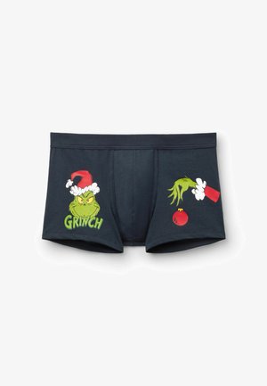 Dark boxer briefs with Grinch's face wearing a Santa hat on the left and his green hand holding a red ornament on the right.